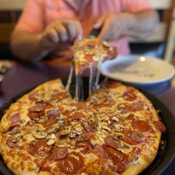 Moose's Tooth Pub & Pizzeria signature dishes The Philly Cheesesteak Pizza, Spicy Chicken Picante Pizza, Chicken Parmesan Pizza, and specialty pizzas like Santa's Little Helper.